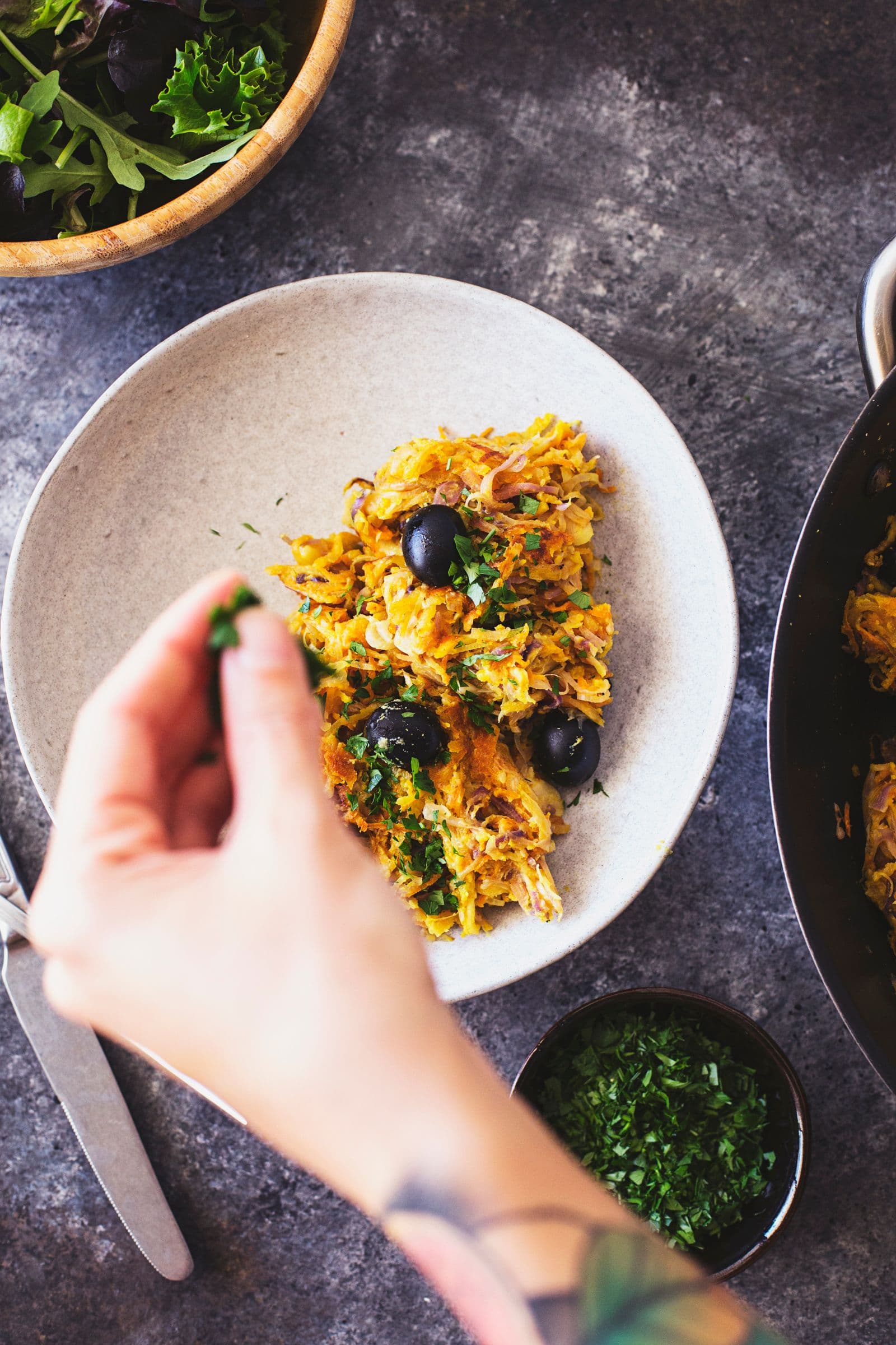 Fresh herbs being sprinkled over a serving of Portuguese veggie hash.